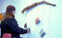 A student views one piece of the “Thantos” exhibit. It consists of books filled with mixed media and quotes that are suspended from a piece of driftwood.