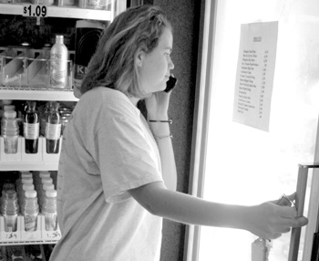 Freshman Kristen McElhaney checks prices on the freezer at the C-Store.