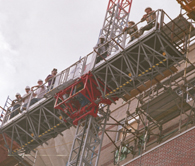 Construction workers catch a lift on the exterior elevator to the seventh floor of Carrollton Hall after a lunch break.