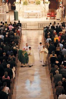 Former Archbishop Francis Shulte leads the procession out of Holy Name Church Sunday at the first mass in the church.