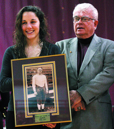 Senior Kiely Schork holds a picture of Ewell Bill Smith Sr. and stands next to his son Feb. 10 at the Hall of Fame induction.