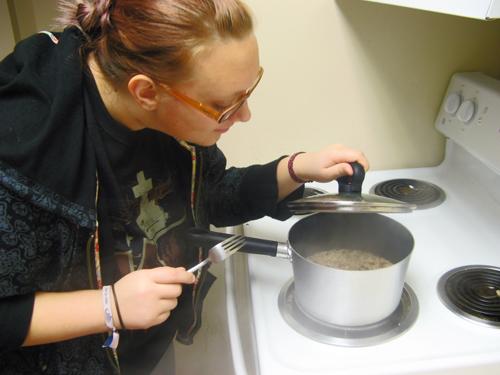 Nichole Adams, math freshman, waits over the stove while her Ramen noodle dinner boils. Ramen is a popular choice amongst students for a quic and cheap meal .