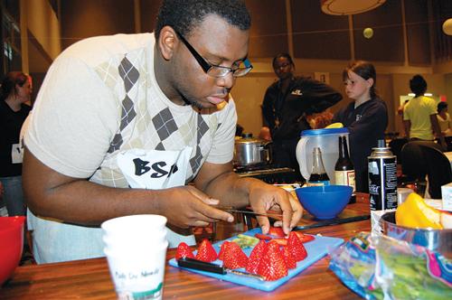 Music Industries sophomore Michael Jackson slices strawberries as he prepares the final dish of his teams three-course meal on Thursday April 2 at the Iron Chef Competition.