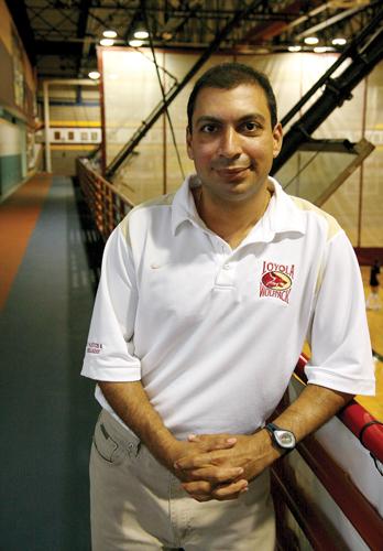 Zubin Engineer, head tennis coach, poses in front of the track inside the University Sports Complex