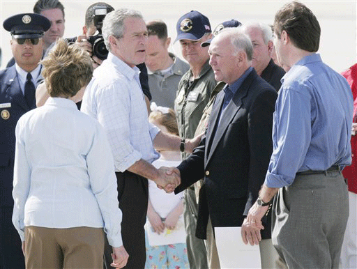** FILE ** This is a March 8, 2006 file photograph of then President George W. Bush and wife Laura, with back to camera, greeting Biloxi Mayor A.J. Holloway, second from right, and other Gulf Coast officials after he toured areas of Gautier, Miss., that were damaged by Hurricane Katrina. The visit was one of several Bush had with Gulf Coast public officials in the state prior to leaving office. Some coastal public officials are disappointed that President Barack Obama's Katrina recovery visit wi