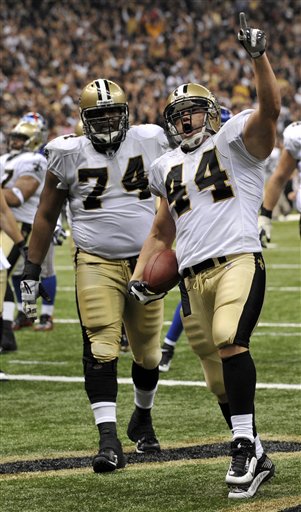 As New Orleans Saints offensive tackle Jermon Bushrod (74) watches, Saints fullback Heath Evans (44) celebrates scoring a touchdown late in the fourth quarter of an NFL football game between the New York Giants and New Orleans Saints in the Louisiana Superdome in New Orleans, Sunday, Oct. 18, 2009. Saints won 48-27.