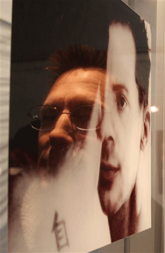 In this photo provided by Bristol-Myers Squibb, David Martin whose reflection appears at left, studies a photo at an exhibit that was submitted to the national "Fight HIV Your Way" photo contest sponsored by Bristol-Myers Squibb in San Francisco, Wednesday, Oct. 28, 2009. More than 1,000 photos and essays were submitted to the contest, designed to help raise awareness about HIV/AIDS and to encourage those impacted by the disease to continue their fight. Martin lost sight in his left eye due to A