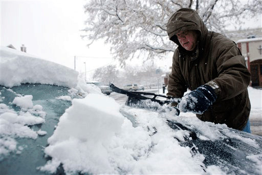 Tracy Buchner, of Denver, uses a brush to clear snow from the windshield of his car as an autumn storm passes through Denver on Sunday, Nov. 15, 2009.