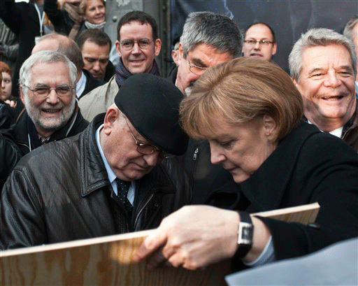 Former Soviet leader Mikhail Gorbachev, left, signs a photograph held by German Chancellor Angela Merkel, in Berlin, Germany, Monday, Nov. 9, 2009, during the commemorations of the 20th anniversary of the fall of the Berlin Wall in 1989