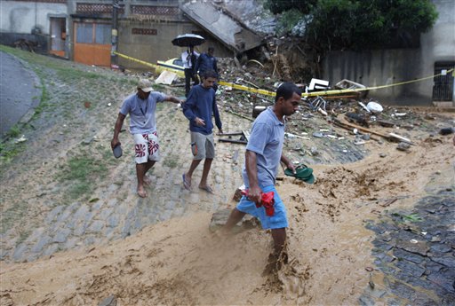 People cross a flooded street in the Morro dos Prazeres area of the Santa Teresa neighborhood in Rio de Janeiro, Tuesday, April 6, 2010. Landslides triggered by torrential rains, killed at least 81 people as rising water inundated Brazil's second-largest city, turning roads into rivers and paralyzing almost all aspects of city life.
