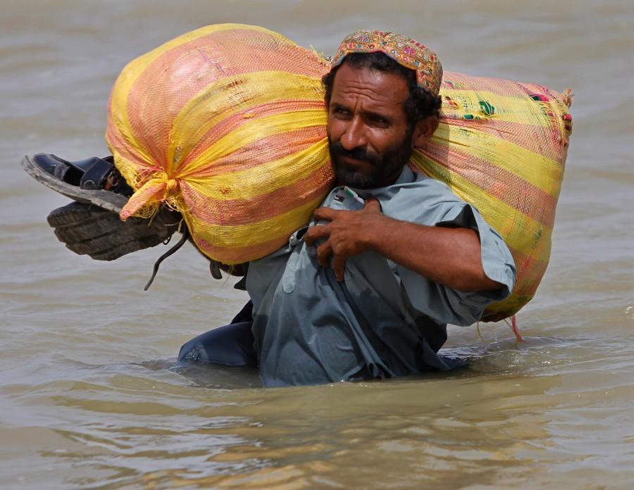 A+Pakistani+man+carries+his+belongings+along+a+flooded+area+at+Sultan+Kot+village%2C+Sindh+province%2C+southern+Pakistan%2C+Tuesday%2C+Sept.+14%2C+2010.