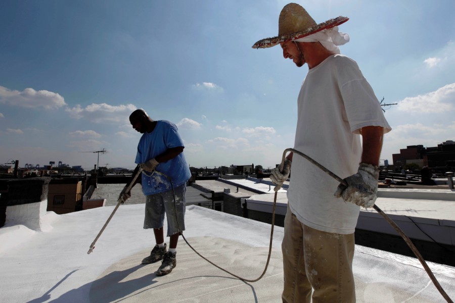 In this Thursday, Aug. 19, 2010 photo, James Peterson, left, and Rory Stout with Bio Neighbors, apply a coating of Acrymax to the roof of a row home in Philadelphia. The idea of painting roofs white has become something of a social movement, one that Energy Secretary (and Nobel Prize-winning physicist) Steven Chu believes could be a huge help in stopping global warming.