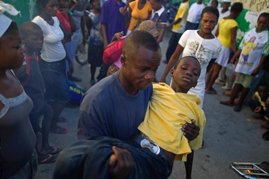 A man carries a child with symptoms of cholera at the entrance of the St. Catherine hospital at the Cite Soleil neighborhood, in Port-au-Prince, Haiti, Thursday, Nov. 11, 2010.