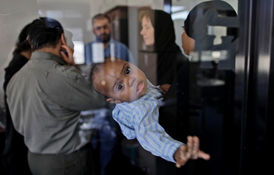Yehya the son of U.S suspect Sharif Mobley, looks on through the glass of a room while his mother Nzinga Islam talks with her U.S. lawyer Cori Crider,second right, shortly before attending a media conference in San'a, Yemen. Mobley, a 26-year old American imprisoned in Yemen for 10 months and accused of ties to al-Qaida had multiple contacts with a radical U.S.-born cleric who is a key figure in the terror group's Yemeni offshoot, his lawyer said Thursday.