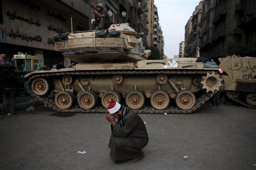 An Egyptian cries in front of on army tank in Tahrir, or Liberation square, in Cairo, Egypt, Wednesday, Feb. 2, 2011. Several thousand supporters of President Hosni Mubarak, including some riding horses and camels and wielding whips, clashed with anti-government protesters Wednesday as Egypt's upheaval took a dangerous new turn.