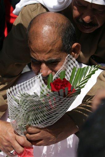 Mourners comfort and hand flowers to Abdulhadi Mushaima Tuesday, Feb. 15, 2011, in Jidhafs, Bahrain,