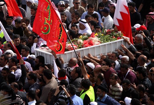 Some thousands of Bahraini mourners participate in a funeral march Tuesday, Feb. 22, 2011, in Malkiya, Bahrain, for Redha Bu Hameed, who died during clashes between army forces and anti-government protesters. The flag reads, "Oh, Hussein," referring to a Shiite Muslim prophet. 