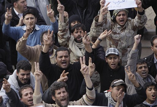 Libyan protesters stand flash V signs as they shout slogans against their Libyan Leader Moammar Gadhafi during a demonstration, in Tobruk, Libya, on Wednesday Feb. 23, 2011. Heavy gunfire broke out in Tripoli as forces loyal to Moammar Gadhafi tightened their grip on the Libyan capital while anti-government protesters claimed control of many cities elsewhere and top government officials and diplomats turn against the longtime leader. 