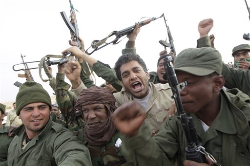 On this image taken during an organized trip by the Libyan authorities for a small group of journalists, Libyan soldiers loyal to Moammar Gadhafi celebrate before pushing forward at the western entrance of the city of Ajdabiya, Libya, Wednesday, March 16, 2011. 