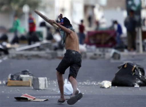 A Shiite Bahraini youth holds a piece of wood in the streets of Malkiya, Bahrain, Wednesday, March 16, 2011, where he and others hauled out debris for barricades and found sticks to use as clubs in preparation for government-supporting forces they expect will role into their Shiite Muslim village southwest of the capital of Manama.