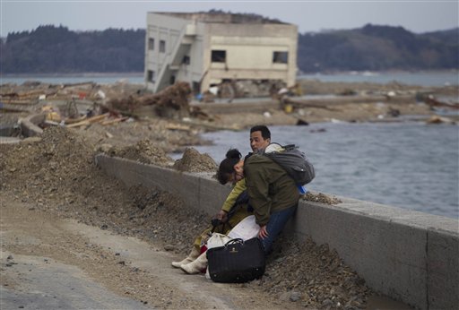 A Japanese couple stop to rest along a highway as they carry their belongings away form their destroyed village of Saito in northeastern Japan, Monday, March 14, 2011. Rescue workers used chain saws and hand picks Monday to dig out bodies in Japan's devastated coastal towns, as Asia's richest nation faced a mounting humanitarian, nuclear and economic crisis in the aftermath of a massive earthquake and tsunami that likely killed thousands.