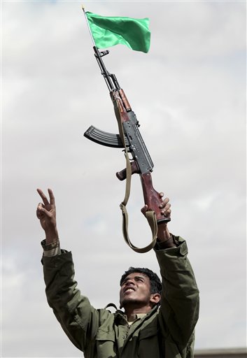 In this image taken during an organized trip by the Libyan authorities, a Libyan supporter of Moammar Gadhafi wearing a uniform displays his new automatic weapon during a staged spontaneous demonstration in Ban-Waled, home of the Warfallah tribe, 160kms (100 miles) south east of Tripoli, Libya, Wednesday March 23, 2011. International airstrikes forced Moammar Gadhafi's tanks to roll back from the western city of Misrata on Wednesday, giving respite to civilians who have endured more than a week 