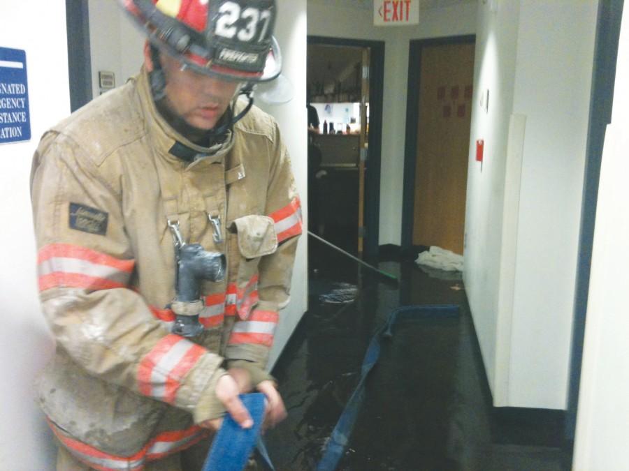 A firefighter caps the broken sprinkler that forced the evacuation of Carrollton Hall Wednesday night. 