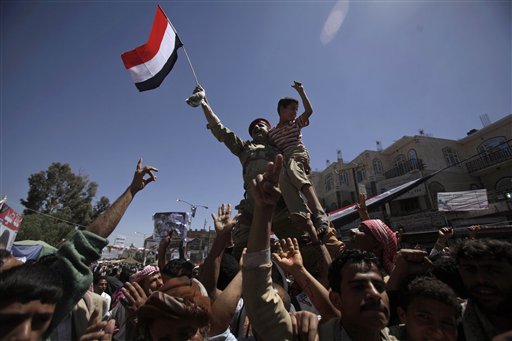 A Yemeni army officer raised aloft by anti-government protestors holds a boy and waves his national flag during a demonstration demanding the resignation of Yemeni President Ali Abdullah Saleh, in Sanaa,Yemen, Monday, April 4, 2011. Yemeni troops opened fire on crowds of protesters demanding the ouster of President Ali Abdullah Saleh, killing six and wounding more than 30 on Monday in the second straight day of clashes in a southern city, witnesses and medical officials said. The bloodshed in th