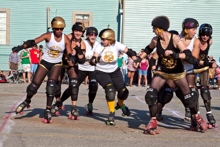 Brooke Ethridge, in white, back, attempts to keep the black team’s jammer from breaking through the pack in the Big Easy Rollergirls exhibition bout held April 2 at the Freret St. Festival. Ethridge is a Loyola English instructor by day and a Big Easy Roller Girl by night.