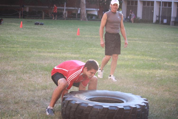 Head Coach Sam Brock watches as Finance  Senior Alex Weed flips a tire at practice on Monday Aug. 29.