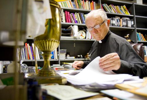 The Rev. James Carter, S.J., president emeritus, grades papers in his office on Dec. 7. Carter said there were 40 Jesuits when he attended Loyola in the 1940s, compared to the 22 now working at the university.