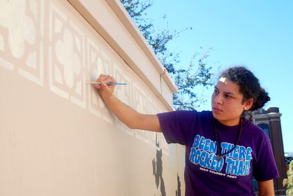 Visual arts graphics senior Hope Henderson paints a detail on “MoWall” Monday, March 5. “MoWall” is the name given to the wooden partition fencing off construction of Monroe Hall that visual arts students designed over with grafitti art.