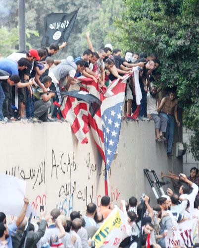 Protesters destroy an American flag pulled down from the US embassy in Cairo, Egypt, on Tuesday, Sept. 11, 2012. Egyptian protesters, largely ultra- conservative Islamists, climbed the walls of the US embassy in Cairo, went into the courtyard and brought down the flag, replacing it with a black flag with Islamic inscription in protest of a film deemed offensive of Islam.