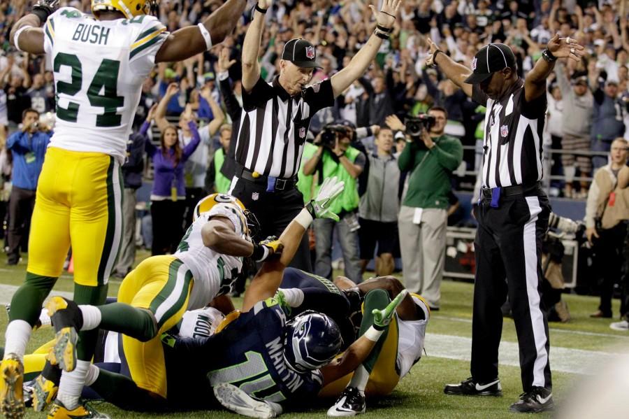 An official signals for a touchdown by Seattle Seahawks as another official signals a touchback. Green Bay lost the game on the last play.