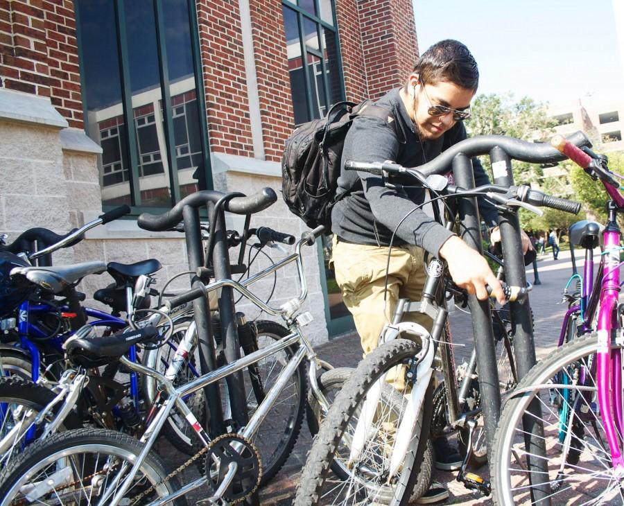 English sophomore Enrique Galvan fastens the lock for his bike outside Monroe Library. Galvan has locked his bike to protect it from the bike theft.