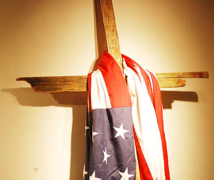 An American flag hangs on the cross in the Collins C. Diboll Art Gallery, which is located on the basement level of the Danna Center. The flag and the cross coincide with the Faithful Citizenship presentation located in the One Loyola Room, which promotes voting consciously.