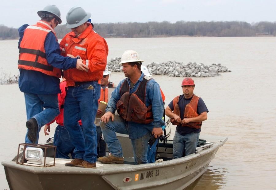 Shannon Warnock, far right, a salvage hand, secures his flotation device after loading a boat. The men land to work on the damaged barge stalled on the west bank of the Mississippi River, Monday, Jan. 28, 2013 near Vicksburg, Miss.