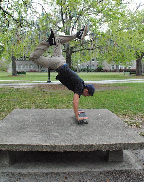 Music industry sophomore Zachary Klos does a handstand on his skateboard during a skating session. Skateboarding has popularized as a sport and leisure activity in the city.  