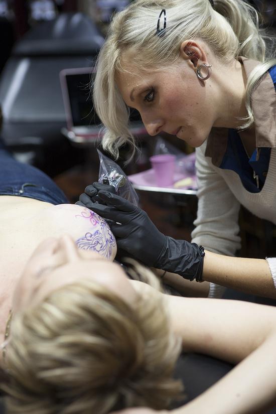 Molly Ortwein, a double mastectomy patient, has her breasts tattooed by UnFamous Miami’s Colby Butler. The inspiration behind Ortwein’s tattoo was Brazil’s pernambuco blossom.