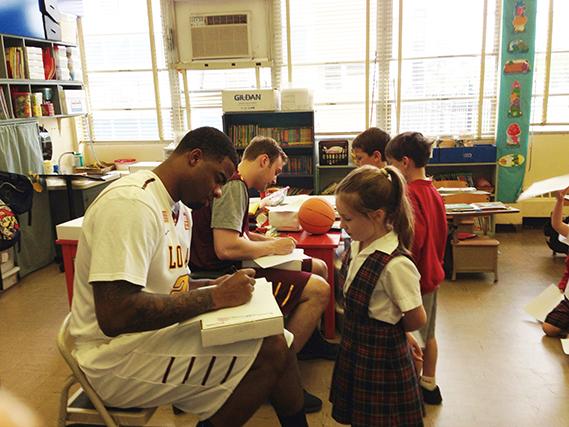 Mass communication junior forward Cameron Hill reads a book to children at St. Mary Magdalene Catholic School in Metairie on April 9. Hill and finance junior McCall Tomeny did community service while representing the Loyola basketball team. 