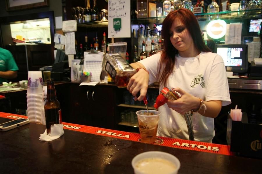 Bartender Caitlyn Bock pours a drink behind the counter at Bruno’s Tavern. Bruno’s is one Uptown bar that restricts entry to those ages 19 and older.