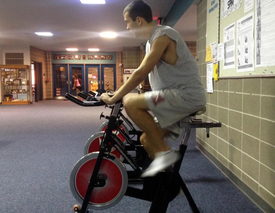 Biology junior Michael Corso trains on exercise bike to rehab his calf injury. Corso hopes to be healthy enough to make the last meet of the season. 