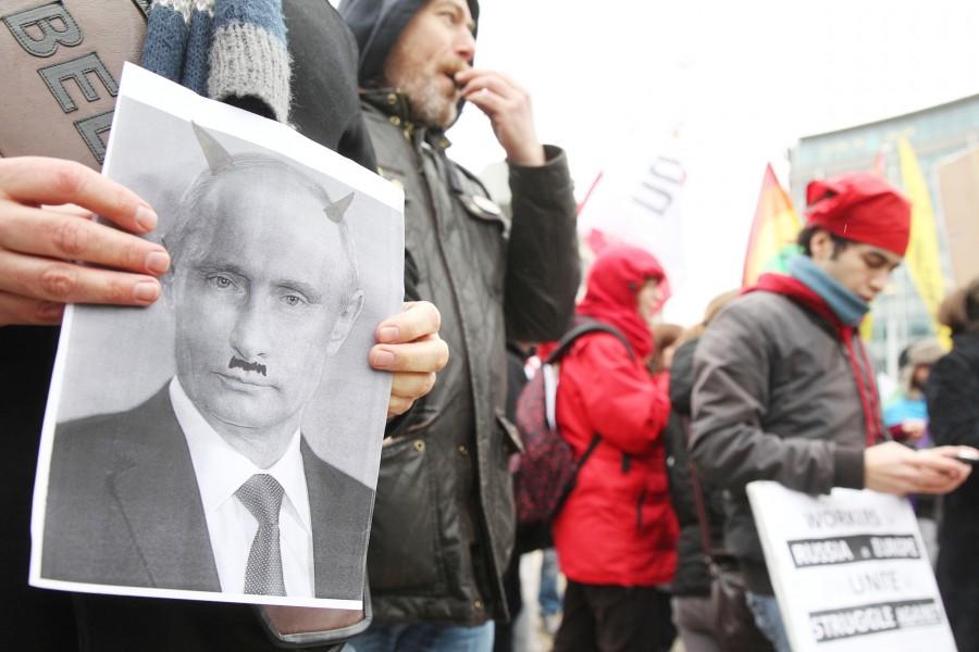 A gay rights activist shows a photo of Russia’s president, Vladimir Putin, depicted as a devil, as protesters gather next to the European institutions in Brussels, Belgium, on Monday,  Jan. 27. Despite months of protests, Russia’s law against ‘gay propaganda’remains in place, but no major boycott of the Russian-hosted Winter Olympics seems likely.