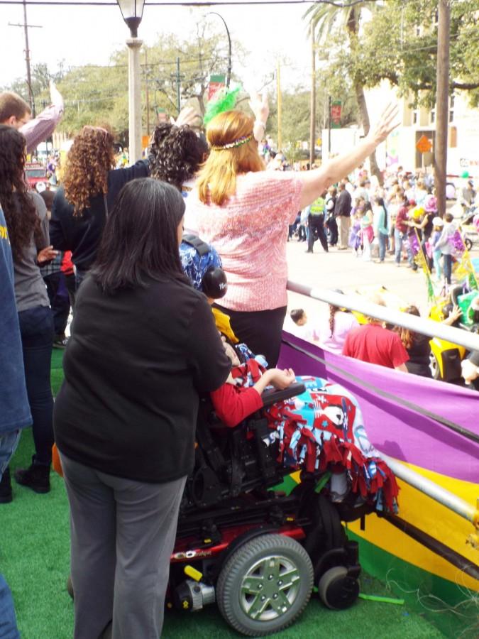 A child and his mother use the Mardi Gras platforms in front of Touro Synagogue at a Mardi Gras parade on Saturday, Feb. 22. Loyola students helped build the platforms as a Mardi Gras service project.