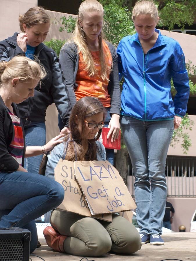 A+woman+kneels+with+a+sign+around+her+neck+to+bring+attention+to+the+treatment+of+homeless+individuals+at+the+Way+of+the+Cross%2FWay+of+Justice+Procession+on+Friday%2C+April+18+in+the+Central+Business+District.+Many+people+attending+the+procession+used+the+event+to+raise+awareness+about+problems+they+saw+in+their+communities.