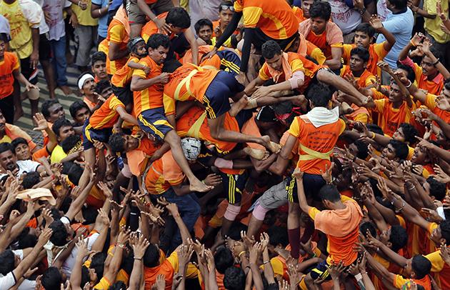 People fall down as they try to form a human pyramid to break the Dahi handi, an earthen pot filled with curd, an integral part of celebrations to mark Janmashtami in Mumbai, India, Monday, Aug. 18, 2014. Janmashtami is the festival that marks the birth of Hindu god Krishna.
