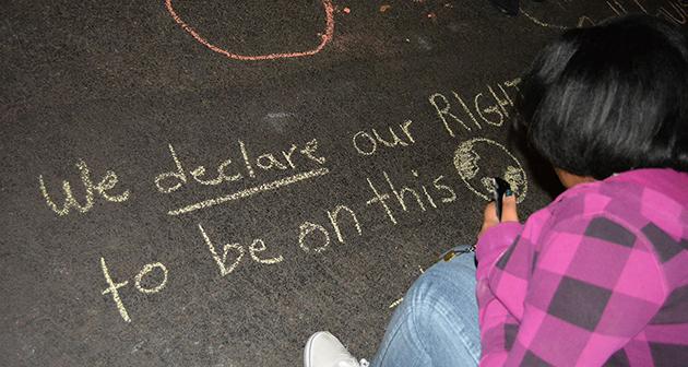 Students write on the pavement as part of a die-in on McAllister Drive.