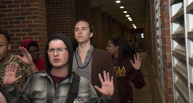 Students raise their hands as they proceed near Carrollton Hall at Loyola.