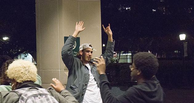 A bystander raises his arms in solidarity as protestors pass.  The student later joined the protestors.