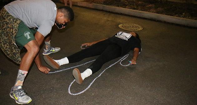 Students trace their bodies on the pavement as part of a die-in on McAllister Drive.